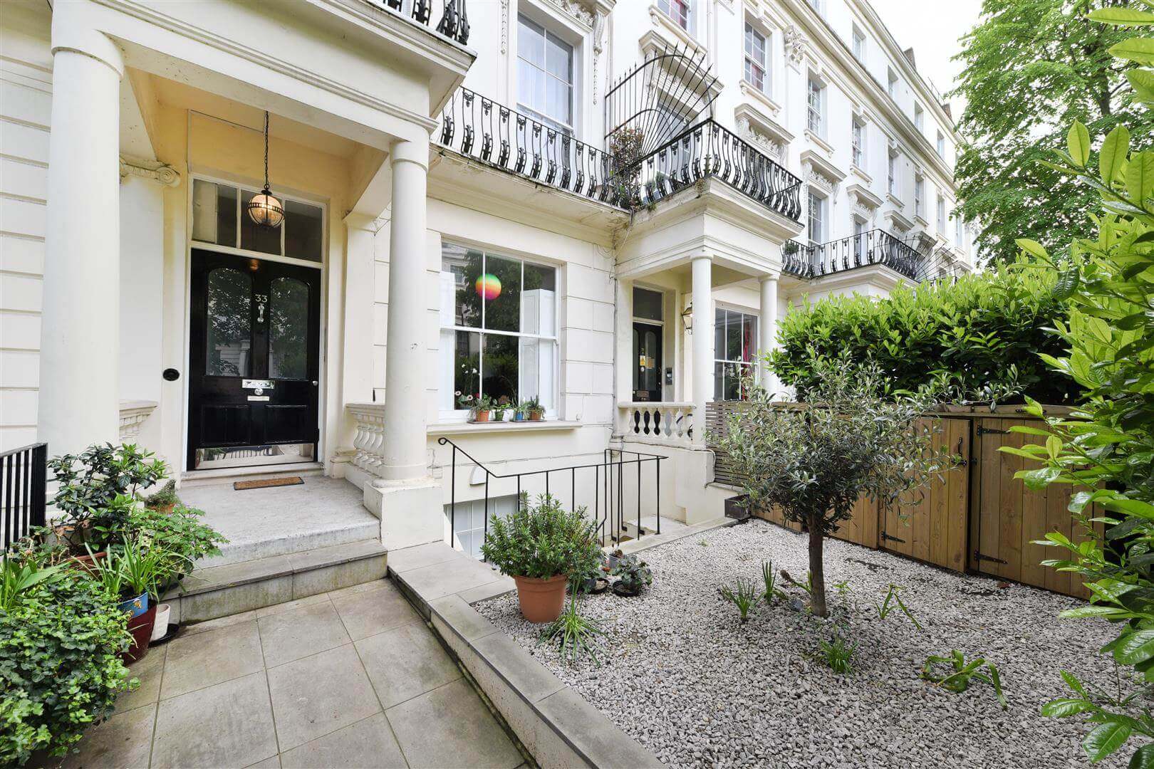 Exterior of a luxury apartment complex with a small front garden surrounded by lush vegetation